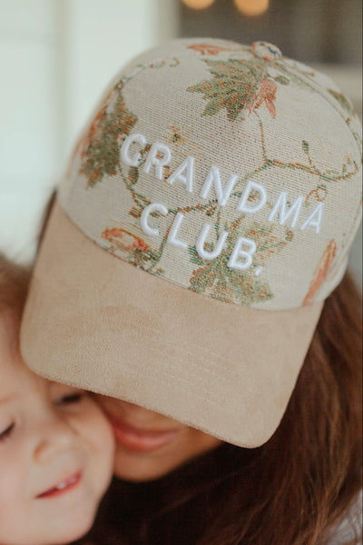 Person wearing a cap with 'Grandma Club' text and a child, blurred background