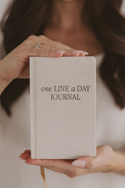Person holding a 'one LINE a DAY JOURNAL' book