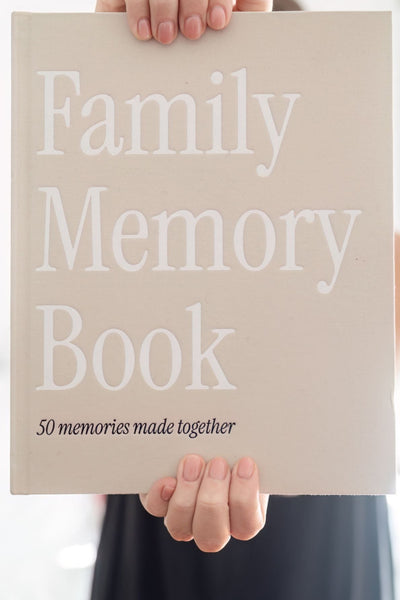 Person holding a 'Family Memory Book' with text on a neutral background