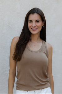 Woman wearing a beige tank top against a plain background