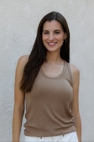 Woman wearing a beige tank top against a plain background