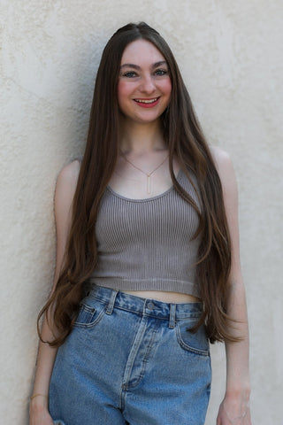 Woman wearing a gray tank top and denim shorts against a beige wall