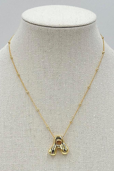 Gold necklace with a pendant on a mannequin bust against a gray background
