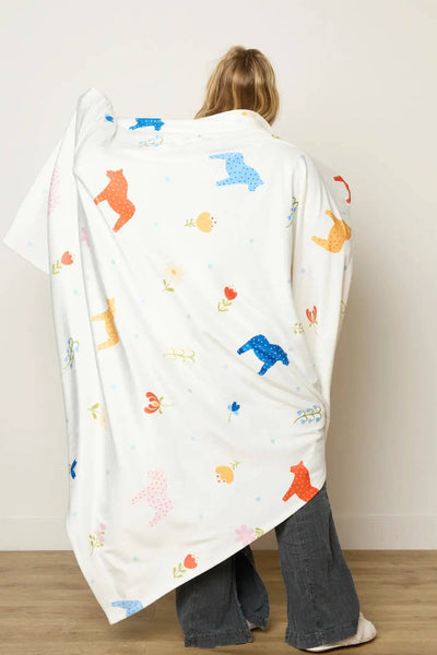 Person wrapped in a colorful patterned blanket against a plain background