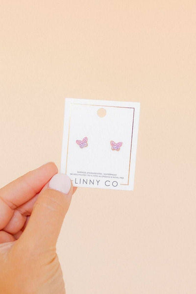 Hand holding a card with butterfly earrings against a beige background