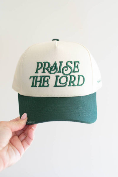 Cap with 'Praise the Lord' text held by a hand on a light background