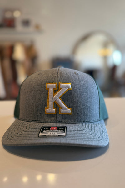 Gray cap with a gold 'K' logo on a blurred background