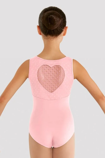 A young girl viewed from the back wearing a light pink sleeveless leotard with a textured heart-shaped back panel, set against a solid light gray background.