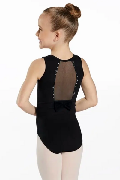 A young girl with her hair in a bun is shown from the back wearing a black sleeveless dance leotard with a sheer mesh back panel, silver studs, and a bow at the back. She is wearing light pink tights against a plain white background.