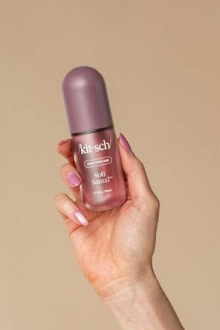 A hand holding a small bottle of bitsch Beauty Glow Serum against a solid beige background.