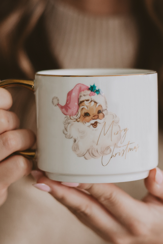 Person holding a Christmas-themed mug with a Santa Claus design.